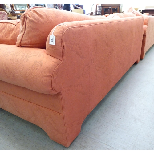 129 - A modern two person settee with a level, low back and scrolled arms, upholstered in burnt orange col... 