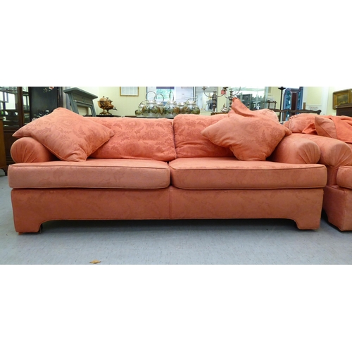 130 - A modern two person settee with a level, low back and scrolled arms, upholstered in burnt orange col... 