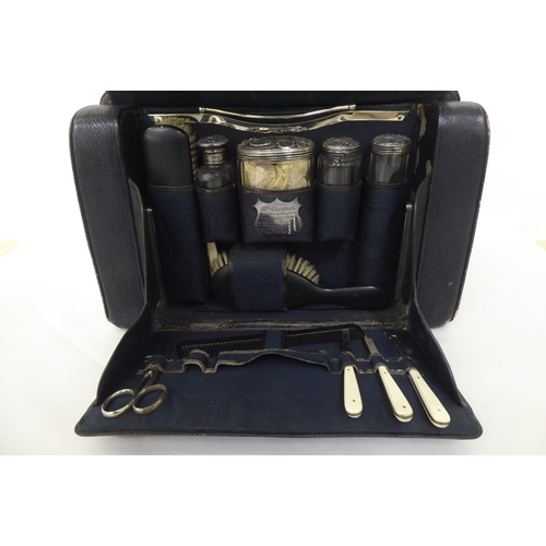 258 - An Edwardian Gladstone style vanity case, containing some silver topped receptacles  marks rubbed