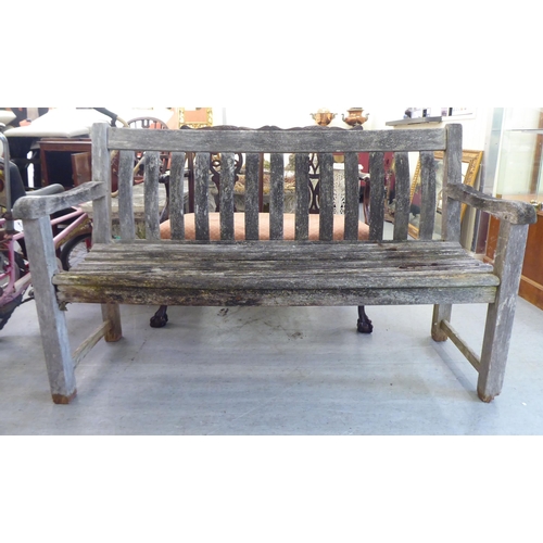 289 - A weathered, slatted teak garden bench, raised on square legs  58