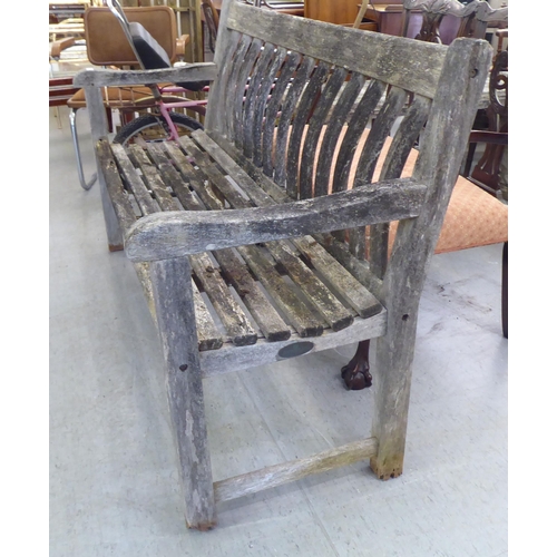 289 - A weathered, slatted teak garden bench, raised on square legs  58