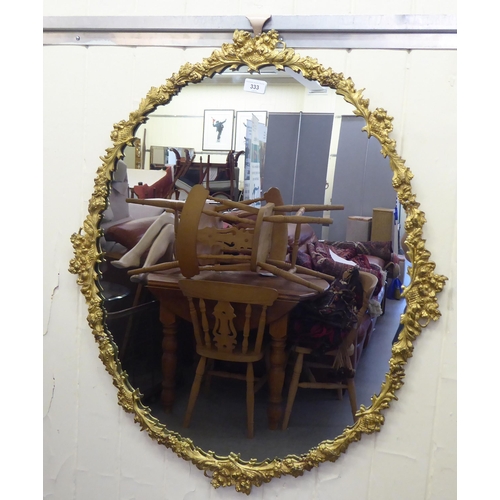 333 - A modern mirror, in a gilt metal frame, encrusted with flora  34