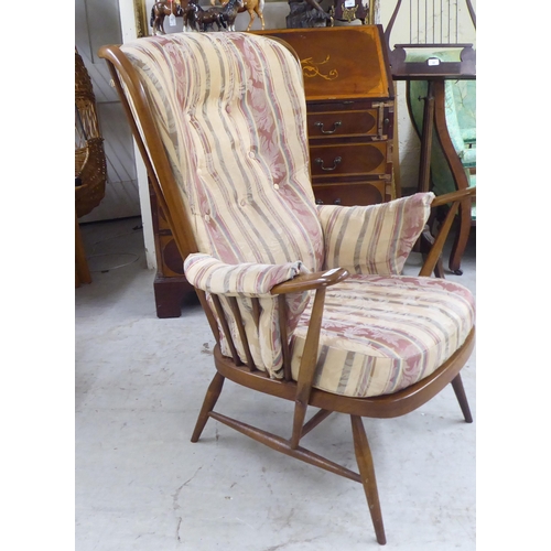 105 - A Ercol beech framed high spindled back armchair, raised on elliptically turned legs