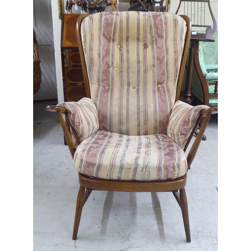 105 - A Ercol beech framed high spindled back armchair, raised on elliptically turned legs