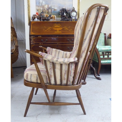 105 - A Ercol beech framed high spindled back armchair, raised on elliptically turned legs