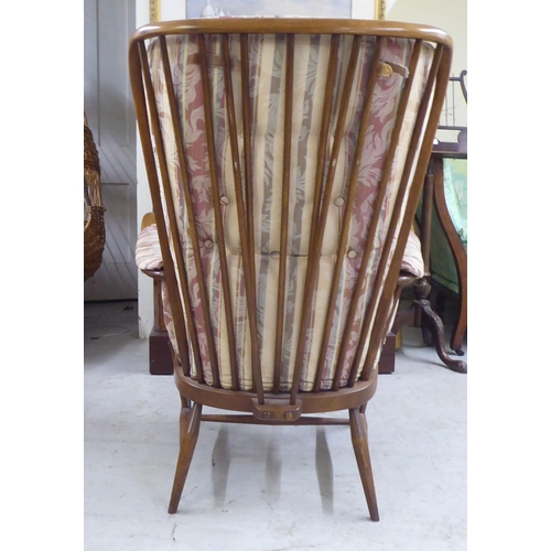 105 - A Ercol beech framed high spindled back armchair, raised on elliptically turned legs