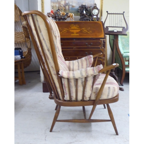 105 - A Ercol beech framed high spindled back armchair, raised on elliptically turned legs