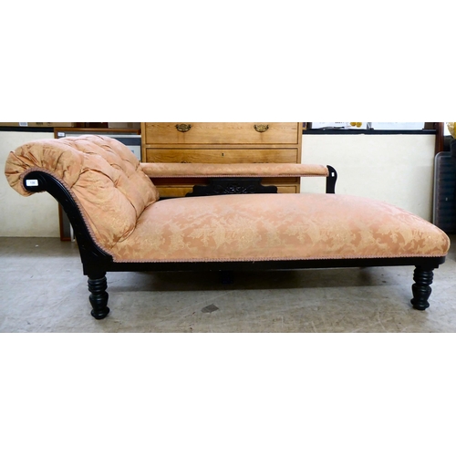 130 - An Edwardian black painted showwood framed chaise longue, upholstered in Oriental patterned fabric, ... 