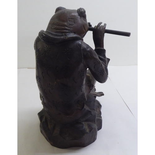 14 - A patinated cast bronze model, a frog seated on a rock, playing a flute  11