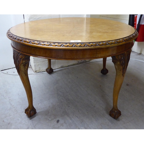 143 - A 1930s walnut coffee table, the top with a piecrust edge, raised on cabriole legs, talon and ball f... 