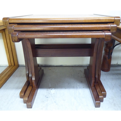 151 - A (probably G-Plan) nesting set of three teak framed tables, the tops set with a spot-hammered coppe... 