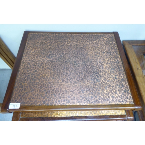 151 - A (probably G-Plan) nesting set of three teak framed tables, the tops set with a spot-hammered coppe... 