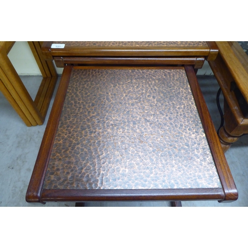 151 - A (probably G-Plan) nesting set of three teak framed tables, the tops set with a spot-hammered coppe... 