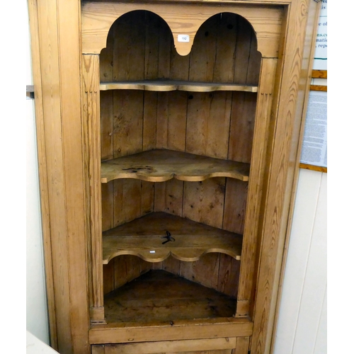 192 - An early 20thC pine corner cupboard, accommodating four open shelves, over a single door, on a plint... 