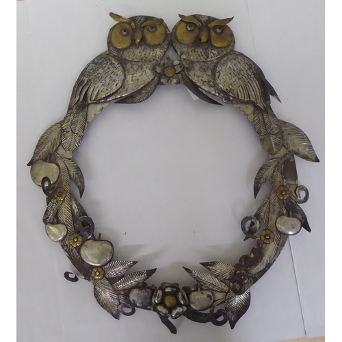 233 - A cast metal picture frame of circular form, decorated with fruiting vines and surmounted by a pair ... 