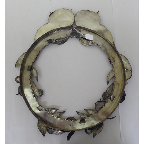 233 - A cast metal picture frame of circular form, decorated with fruiting vines and surmounted by a pair ... 