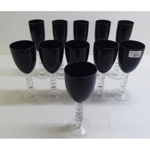 27 - Two sets of dark red coloured glass, viz. five flutes and six pedestal wines, on knopped stems