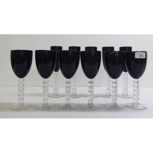 27 - Two sets of dark red coloured glass, viz. five flutes and six pedestal wines, on knopped stems