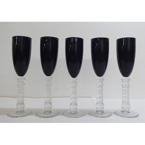 27 - Two sets of dark red coloured glass, viz. five flutes and six pedestal wines, on knopped stems