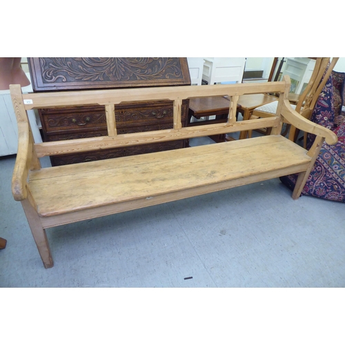 273 - A modern pine bench, the canted bar back and open arms enclosing a cushioned seat, raised on tapered... 