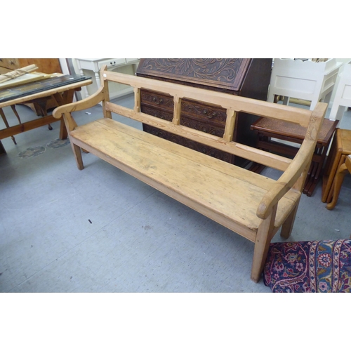 273 - A modern pine bench, the canted bar back and open arms enclosing a cushioned seat, raised on tapered... 