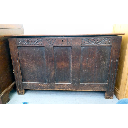 277 - A late 18thC oak coffer with a hinged lid and a tri-panelled front, raised on block feet  28