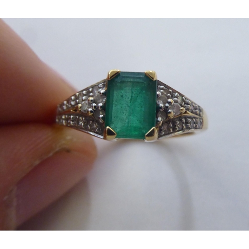 297 - An 18ct gold ring, set with a central octagon cut emerald, flanked by diamonds