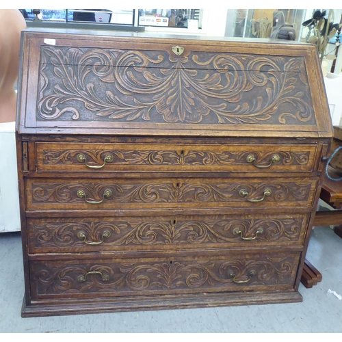 316 - An early 20thC carved oak bureau, the fall front over four long drawers, on a plinth  40.5