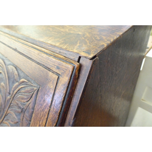 316 - An early 20thC carved oak bureau, the fall front over four long drawers, on a plinth  40.5