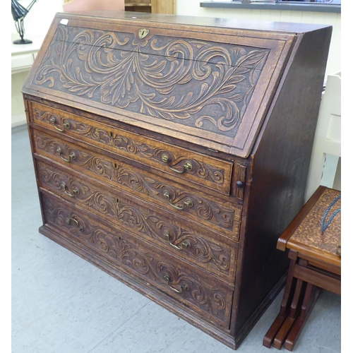 316 - An early 20thC carved oak bureau, the fall front over four long drawers, on a plinth  40.5