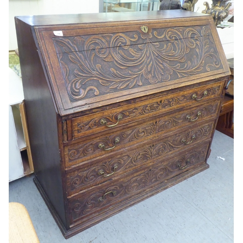 316 - An early 20thC carved oak bureau, the fall front over four long drawers, on a plinth  40.5