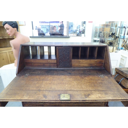 316 - An early 20thC carved oak bureau, the fall front over four long drawers, on a plinth  40.5