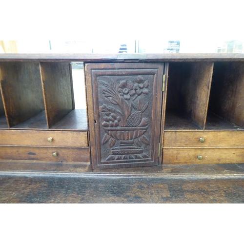 316 - An early 20thC carved oak bureau, the fall front over four long drawers, on a plinth  40.5