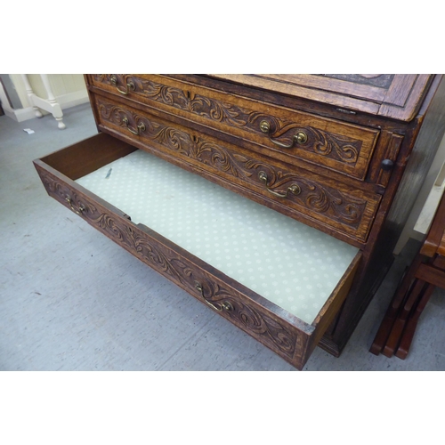 316 - An early 20thC carved oak bureau, the fall front over four long drawers, on a plinth  40.5