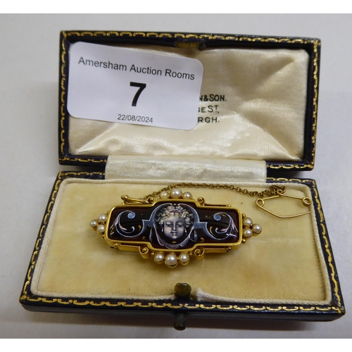 7 - A late Victorian yellow metal mourning brooch with enamelled decoration, set with seed pearls