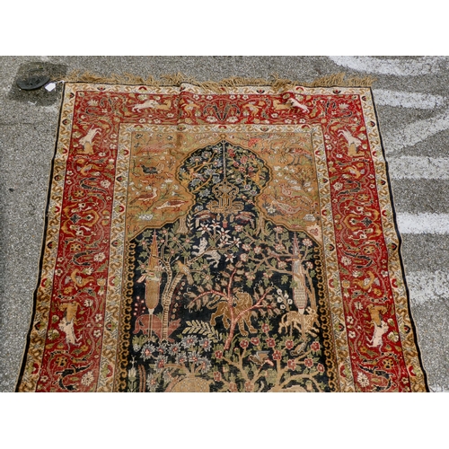 226 - An early 20thC Persian rug, decorated with a central tree of life motif, surrounded by wild animals ... 