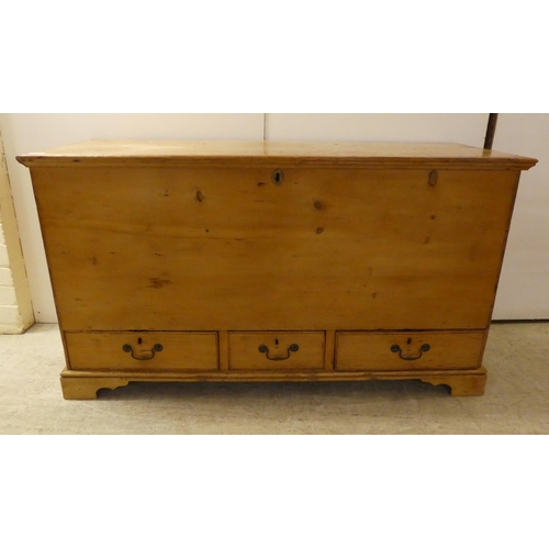 120 - An early 20thC rustic pine trunk with straight sides and a hinged lid with three in-line drawers, ra... 