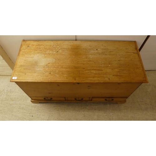 120 - An early 20thC rustic pine trunk with straight sides and a hinged lid with three in-line drawers, ra... 