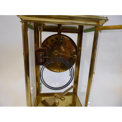 176 - A mid 20thC lacquered brass cased, four glass mantel clock with bevelled panels and a platform top, ... 