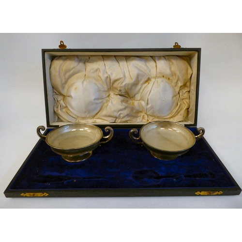 180 - A pair of silver twin handled sweet dishes, on pedestal footrims with glass liners  Rainforth &... 