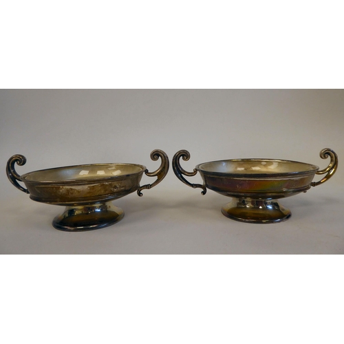 180 - A pair of silver twin handled sweet dishes, on pedestal footrims with glass liners  Rainforth &... 