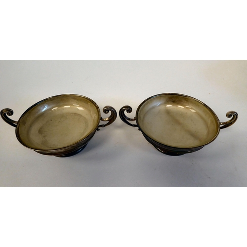 180 - A pair of silver twin handled sweet dishes, on pedestal footrims with glass liners  Rainforth &... 