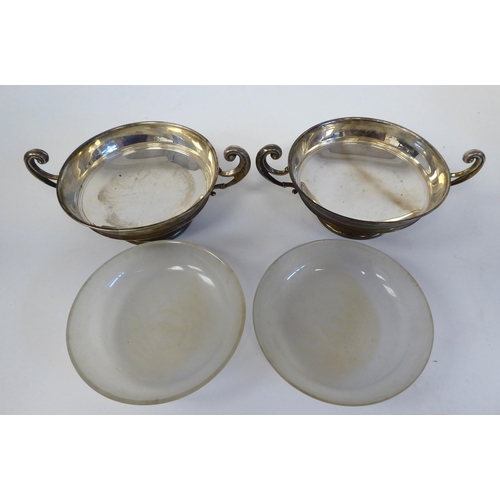 180 - A pair of silver twin handled sweet dishes, on pedestal footrims with glass liners  Rainforth &... 