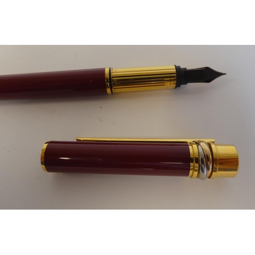 185 - A Must de Cartier gilt and maroon cased fountain pen with an 18k nib  No.041653