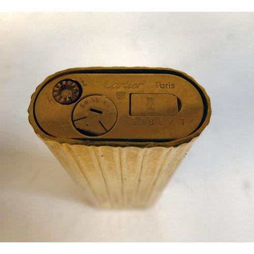 196 - A Cartier gold plated, cased, gas filled cigarette lighter of oval, reeded form  No.53809T, in ... 