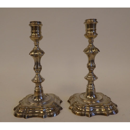 244 - A pair of George IV silver candlesticks, each on a stepped serpentine outlined plinth  indistinct ma... 