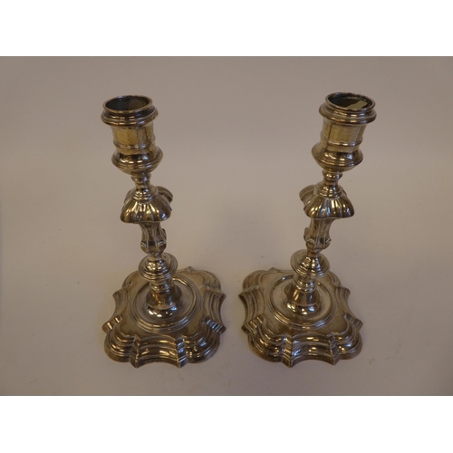 244 - A pair of George IV silver candlesticks, each on a stepped serpentine outlined plinth  indistinct ma... 