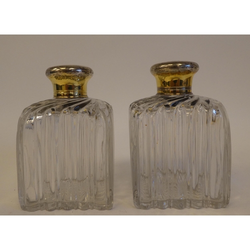 248 - A pair of late 19th/early 20thC clear glass scent bottles of shouldered, ribbed form with rubbed sil... 