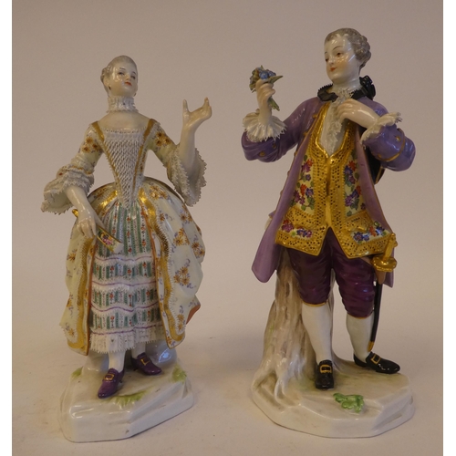 265 - A pair of mid 19thC Meissen porcelain figures, viz. a woman wearing a ballgown, holding a fan  impre... 