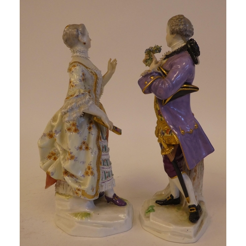 265 - A pair of mid 19thC Meissen porcelain figures, viz. a woman wearing a ballgown, holding a fan  impre... 